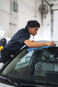 Employee at Liberty Autoworx wiping ceramic coating off a windshield in Edmonton, AB